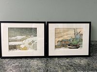 Photo showing both framed prints side by side on a gray countertop against a white wall, displaying their full size and framing.