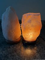 Two Himalayan salt lamps on countertop; one illuminated showing warm orange glow, other unlit
