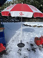 Full view of the red and white Rainier Beer advertising umbrella standing open in snow.