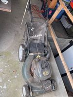 Full view of Craftsman lawnmower with attached grass catcher bag and handle bars in a garage setting with visible dust and wear.