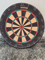 Front view of the full dart board showing the circular design, numbering, and colored scoring segments.
