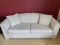Front view of double sofa bed with two throw pillows against red wall