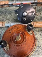Close-up photo of wooden Peetz 425 fishing reel and black Penn reel mounted on fishing rods with cork handles