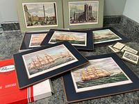 Overview of 6 Pimpernel placemats with sailing ship prints, 3 coasters, 2 framed city prints, and original box