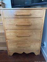 Front view of vintage 4 drawer maple dresser showing drawer handles and base details.