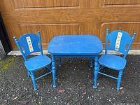 Full view of the blue painted wooden children's table with two matching chairs showing overall condition and stickers on chairs.