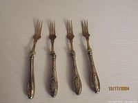 Photo showing all four forks laid out in a row, displaying their tines and handles with visible tarnish and wear.