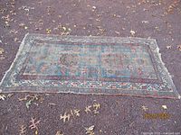 Full view of the antique oriental runner rug laid flat on ground with visible wear and faded colors.