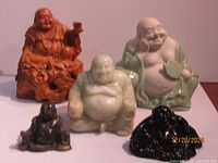 Five Laughing Buddha statues of various sizes and materials including marble and resin, arranged together