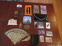 Full overview of lot showing various vintage and collectible items including fan, wallets, bottle opener, small cases, coins, pins, and photos.