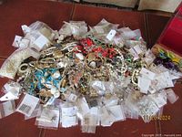 Wide view of assorted broken costume jewelry mixed with various packaged jewelry supplies on a brown surface.