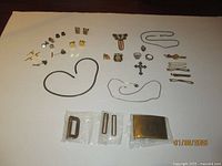 Full overview of men's jewelry collection including tie clips, rings, pins, necklaces, pendants, cuff links, belt buckles, and vintage bookmark.