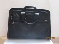 Front view of black Tumi briefcase showing dual zipper compartments and handles