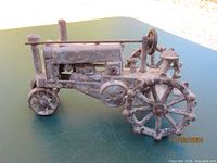 Side view of the cast iron tractor showing detailed wheels, smokestack, and engine features with rust.