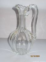 Front view of large clear glass ewer showing its bulbous body and tall neck