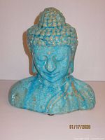 Front view of turquoise blue ceramic Buddha bust with crackled glazed finish showing facial features and shoulders.