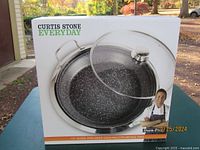 Box front image showing Curtis Stone Everyday 12-inch Dura-Pan deep dish multipurpose pan with lid and branding details.