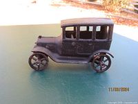 Side view of the antique Arcade cast iron toy car showing body and wheels with rust.