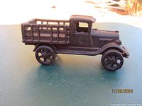 Side view of antique cast iron Ford delivery truck model showing detailed wheels and slatted bed sides.