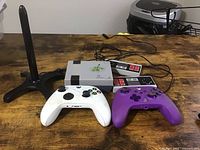 Overview of the video console, controllers and antenna stand on wooden surface