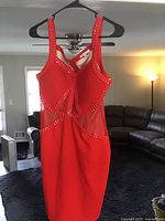 Front view of red women's dress on a black hanger, showing detailed bead work on bust and fitted design.