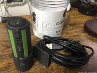 Coluk branded dash cam standing upright with USB cable coiled beside it on wood surface.
