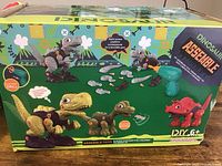 Photo of the toy set packaging showing the dinosaur assemble parts, colorful dinosaur models, and electric drill illustration.