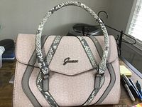 Front view of Guess ladies purse showing pink and gray pattern, handle, and logo.