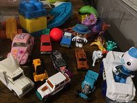 Assortment of used toy vehicles including cars, trucks, and small animal figures