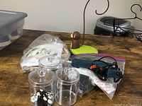 Glass containers alongside a blue glue gun, a duck-shaped jewelry holder, and other items on a wood table.