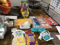 Wide view of lot showing glue sticks, pencils, sticky notes, tape dispenser, glue gun, markers, and stationery items on table