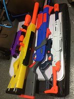 Four Nerf toy blasters laid out on a table, showing different styles and colors.
