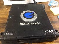 Top view of Planet Audio AC1500.1M power amplifier showing branding, model number and power rating.