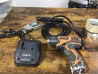 Wide view of the Ridgid drill, PowerSmart charger, and DMC cable grounding set on wood surface showing items together