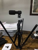 Aitechny microphone mounted on the tripod stand, with instruction manual nearby on wooden table.