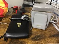 Black and white Pomelo purses displayed on a wooden table showing size and strap details.