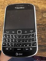 Close up view of the vintage Blackberry phone showing physical keyboard and AT&T branding.