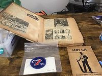 Open scrapbook showing yellowed pages with newspaper clippings and black and white photos from World War 2 era.