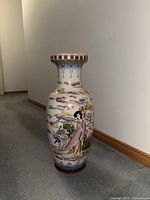 Full side view of tall porcelain vase depicting a lady in traditional clothes with colorful cloud and landscape designs, standing on carpeted floor near a wall.