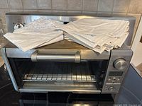 Front view of the Breville Mini Smart Oven with kitchen linens placed on top.