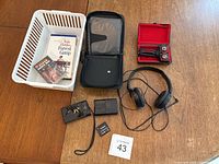 Lot overview with camera, battery, charger, headphones, DVD and VHS media, and plastic holder case.