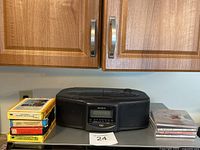 Sony black stereo CD player with built-in speakers, placed on countertop under wooden cabinet.