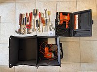 Photo showing Black & Decker 2-speed drill and sander in cases beside various hand tools arranged on floor.