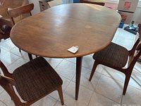 Full view of oval teak dining table with four chairs surrounding it