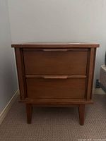 Front view of mid-century modern wooden end table with two drawers, showing overall structure and design.