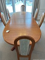 Oval teak table extended with chairs in background