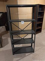 Front view of black metal utility shelf with four shelves and cross brace on the back.