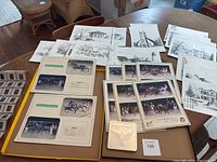 Wide view of the sketches, horse racing prints in albums, and slide collection arranged on a table.