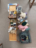 Top view of vintage wooden sewing box opened showing its compartments filled with various sewing tools, scissors, and buttons alongside skeins of yarn and the embroidered bag on carpet.