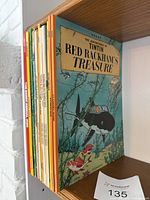 Bookshelf with vintage comic books including The Adventures of Tintin featuring Red Rackham's Treasure and others organized vertically